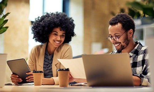 man and woman sitting at a table with a laptop