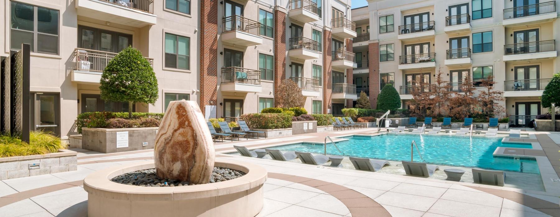 a fountain and pool in a courtyard with buildings in the background