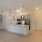 a kitchen with white cabinets and living room with wood flooring