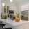 a kitchen with white cabinets and an island with seating and a bowl of oranges on it