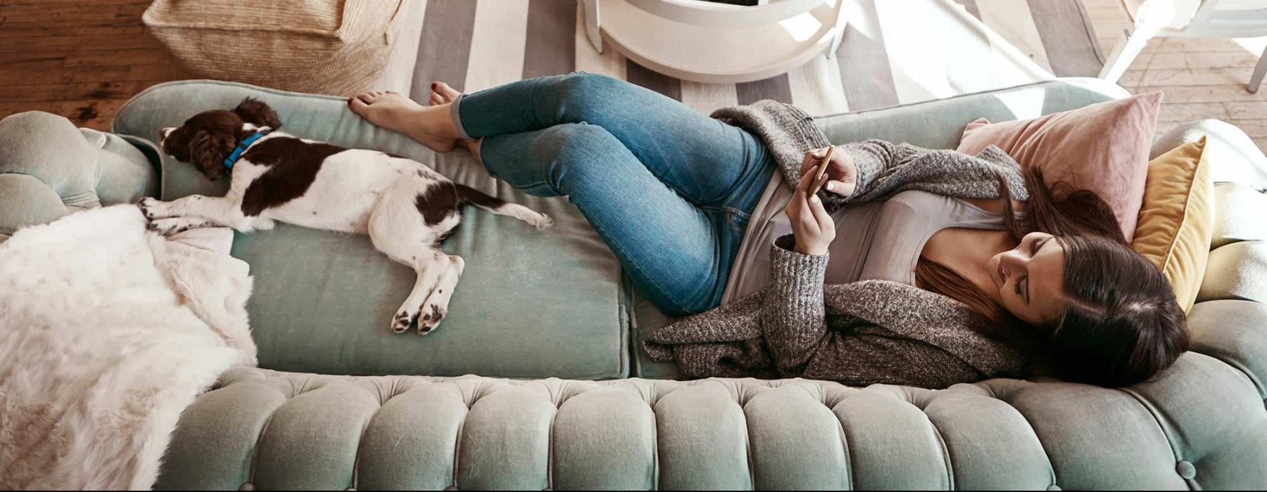 a woman and a dog laying on a couch with a phone