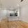 a kitchen with white cabinets and living room with wood flooring